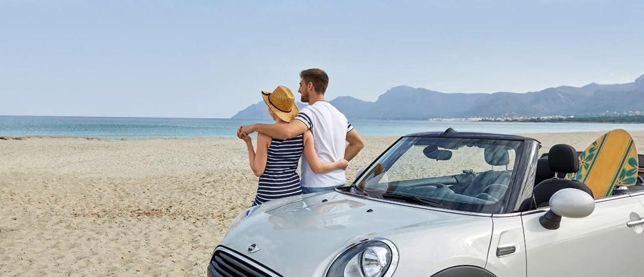 Paar am Strand am Austin Mini lehnend