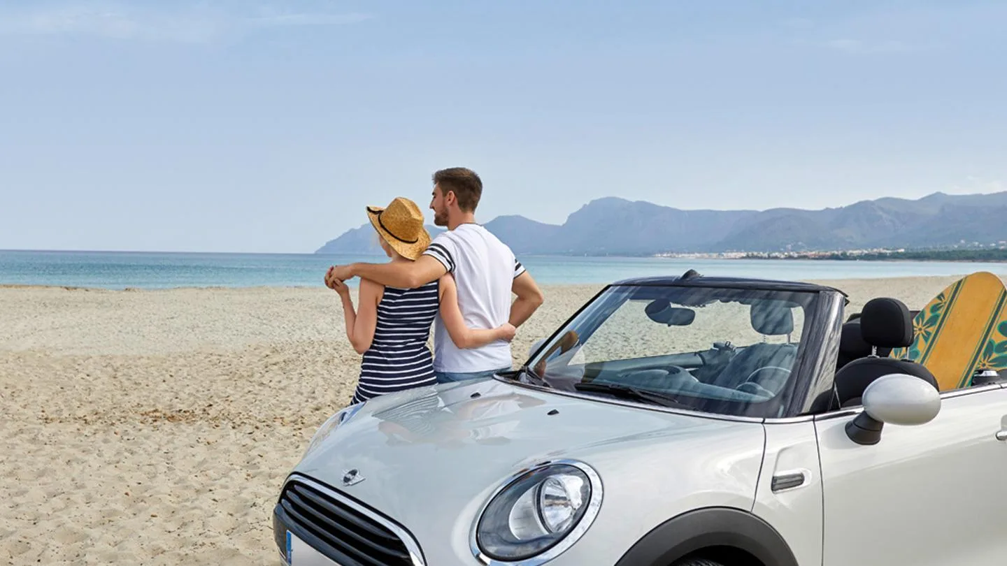Paar an Austin Mini lehnend am Strand